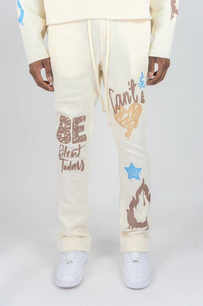 Cream Rebel Minds 'Can't Be' stacked fleece sweatpants with relaxed fit and elastic waistband, displayed on a hanger.